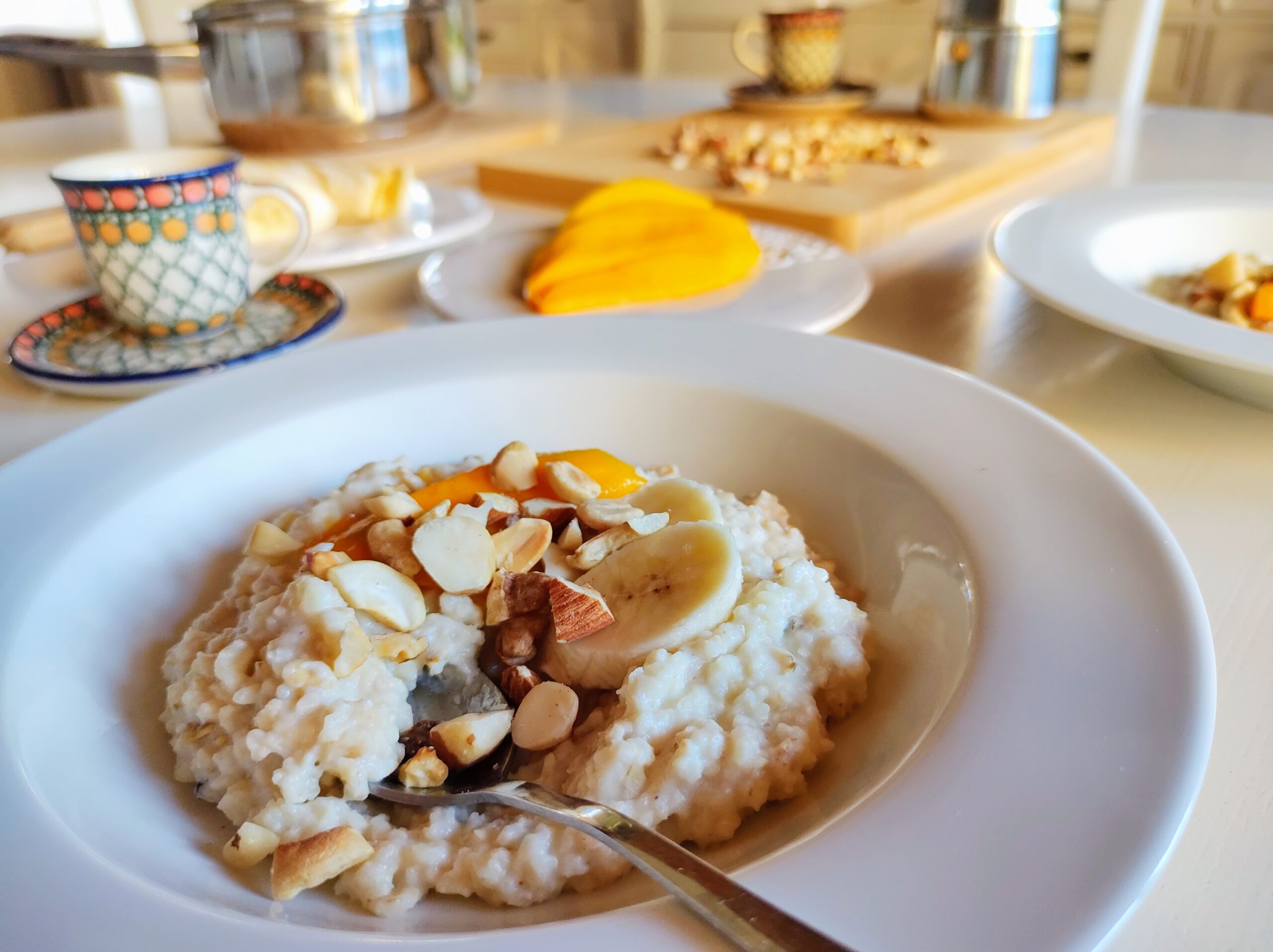 Stół przygotowany do śniadania, na stole talerze, a w nich owsiana jaglanka na mleku kokosowym.